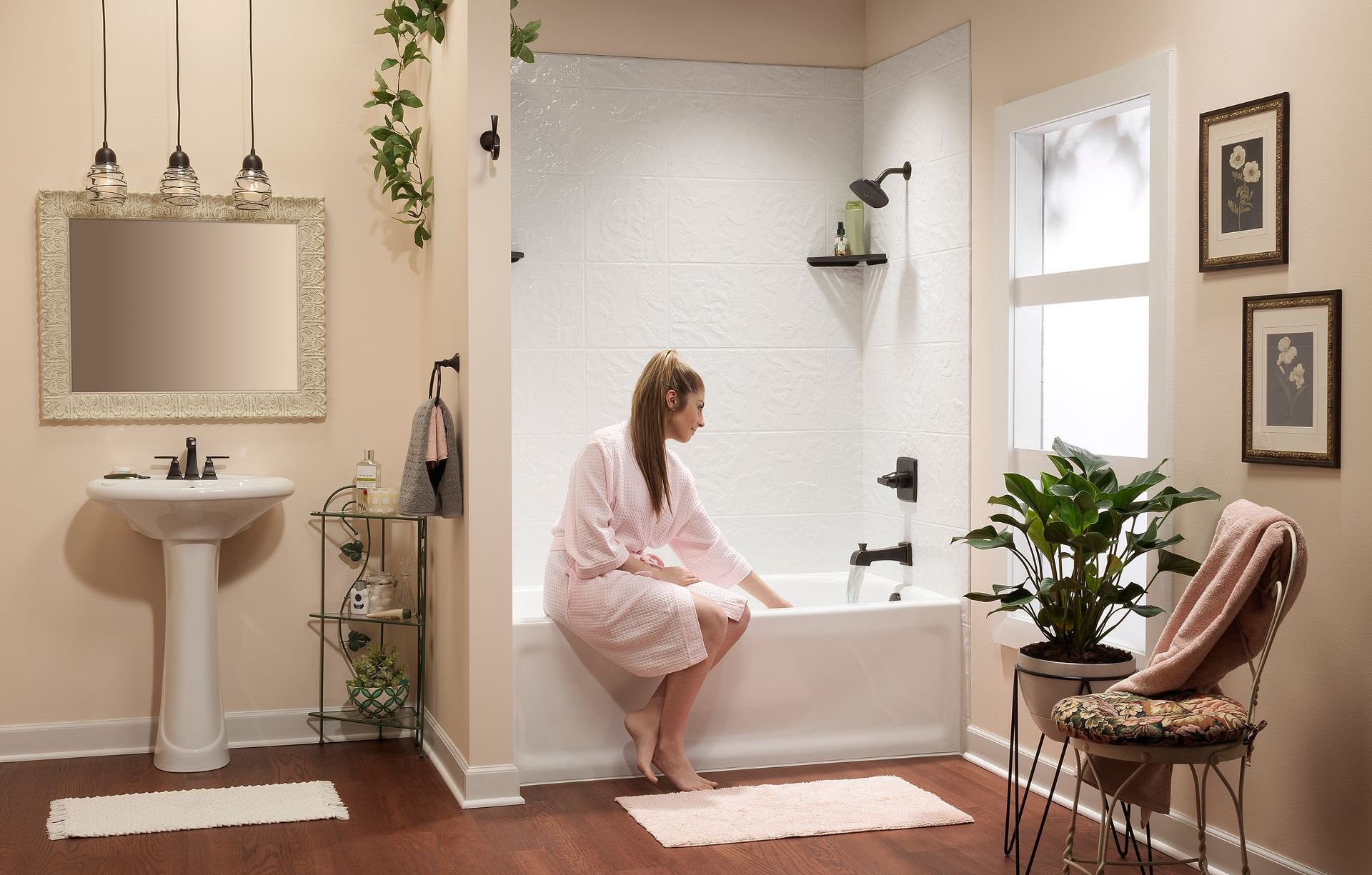 Woman in robe sits on tub edge in a bathroom. She is reaching into the water.