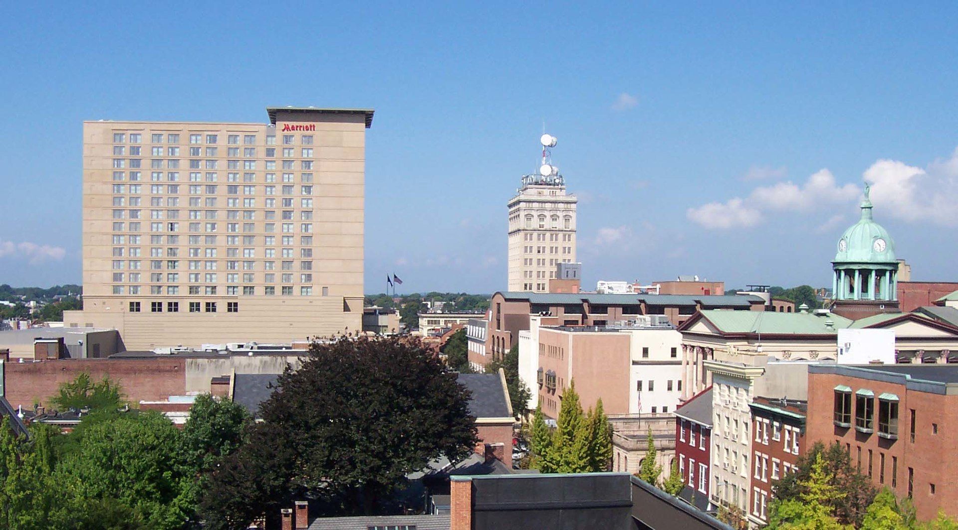 Skyline with tall buildings including a hotel and a domed building, under a clear blue sky.