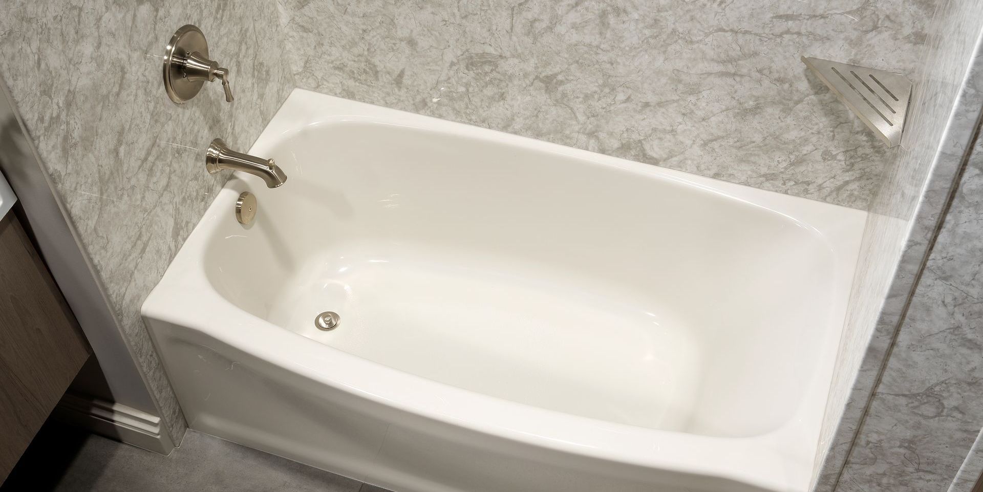 White bathtub with silver faucet in a bathroom with gray wall paneling.