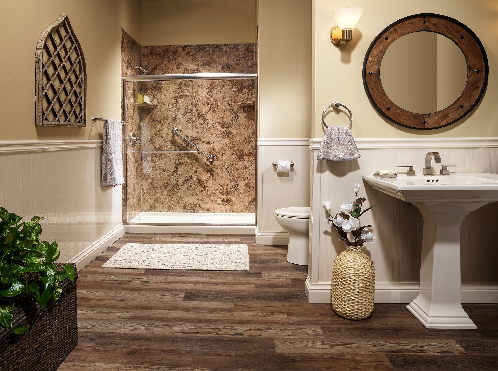 Bathroom with a pedestal sink, shower, and toilet. Dark wood-look floor, light walls, and a decorative mirror.