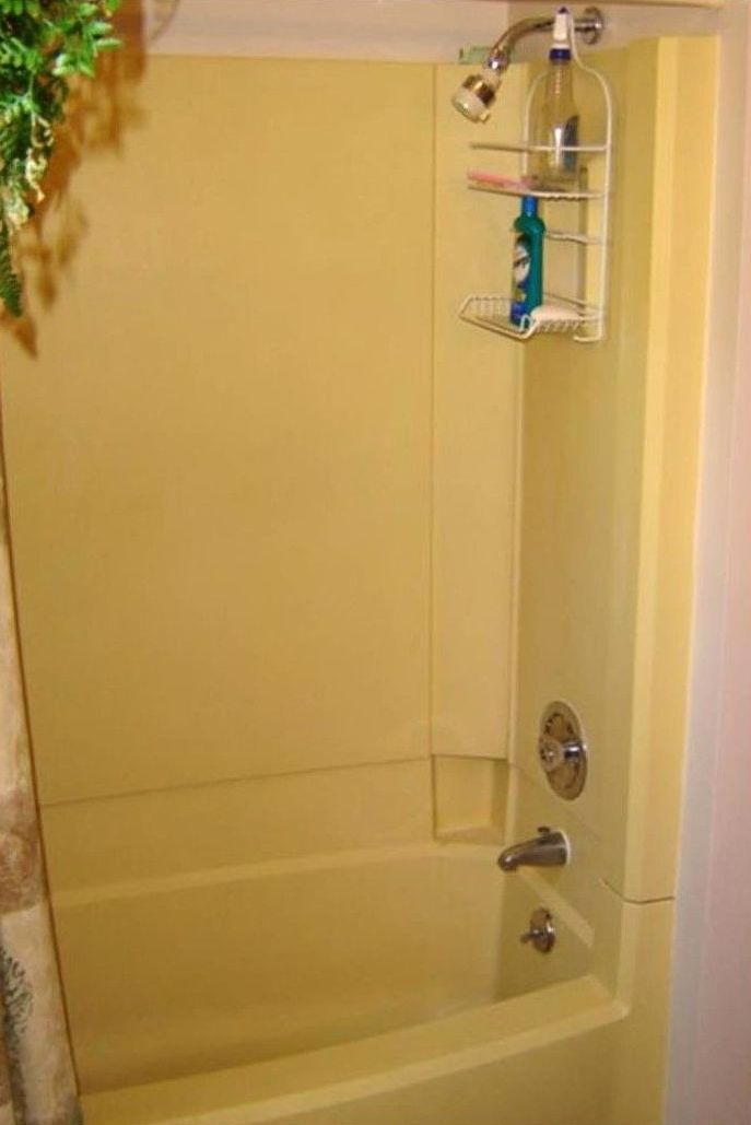 Yellow bathtub and shower combo with a built-in shelf holding toiletries.