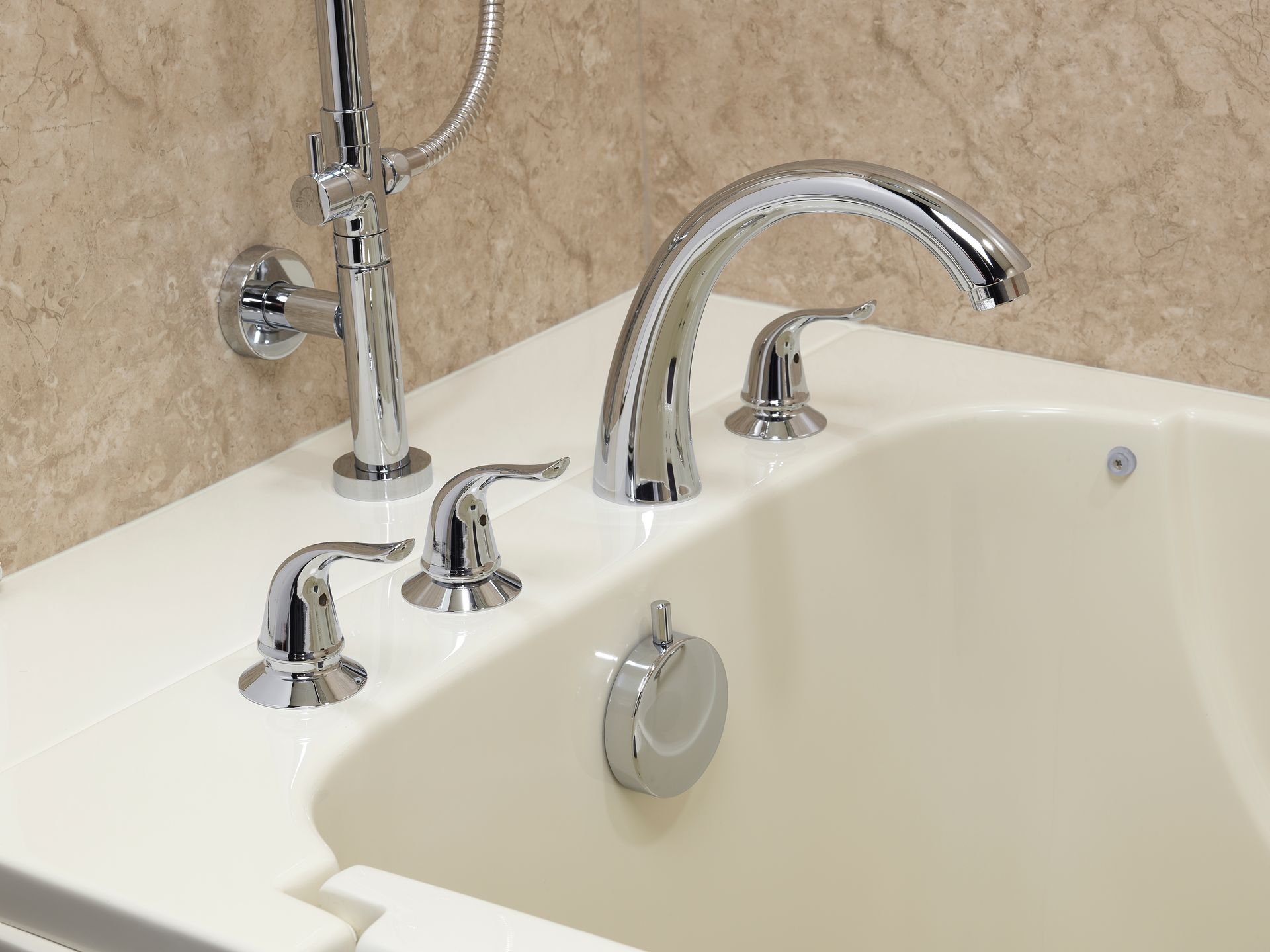 Close-up of a bathtub with chrome fixtures, including a faucet, two handles, and a shower head.