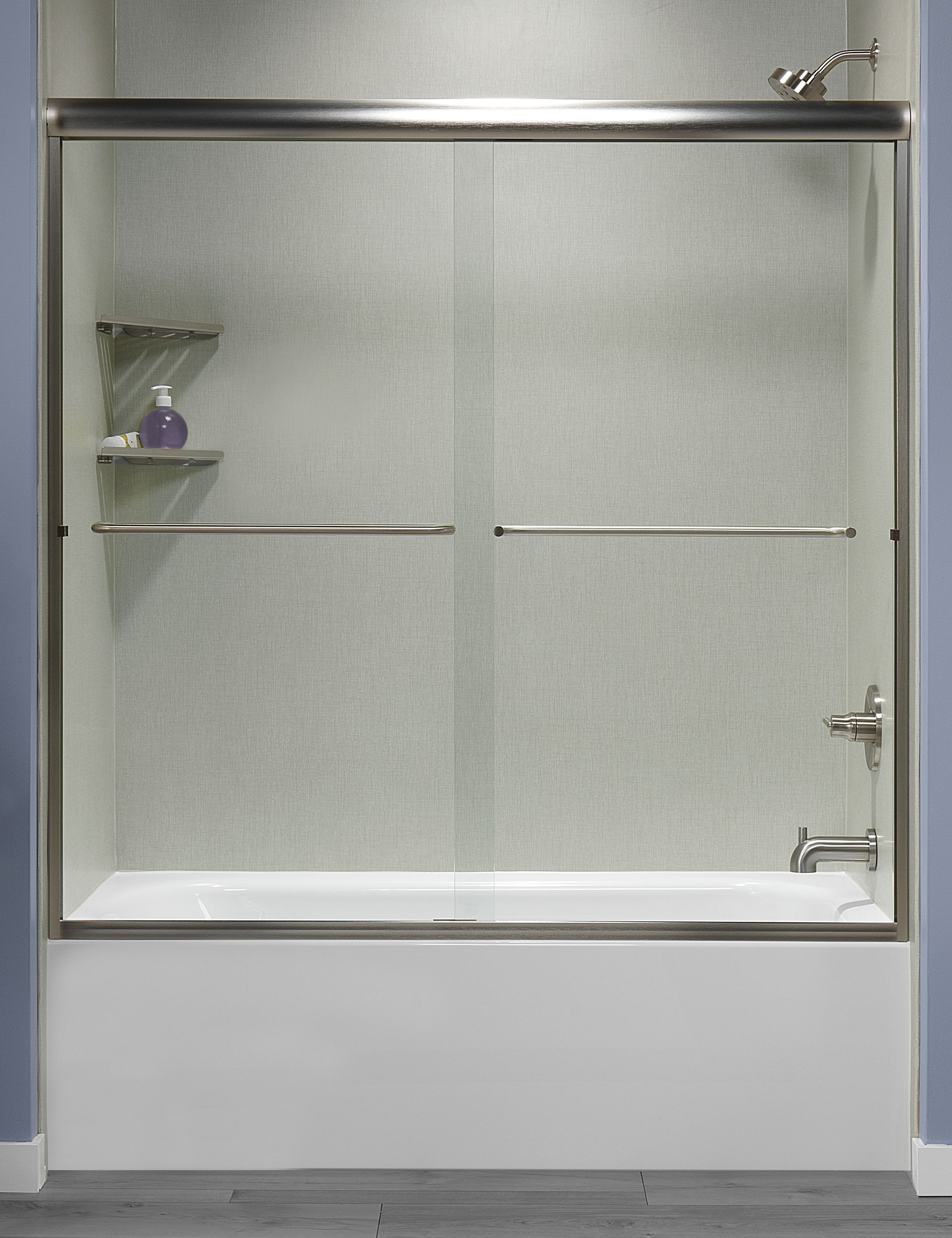 Shower enclosure with sliding glass doors, stainless steel frame, over a white bathtub.