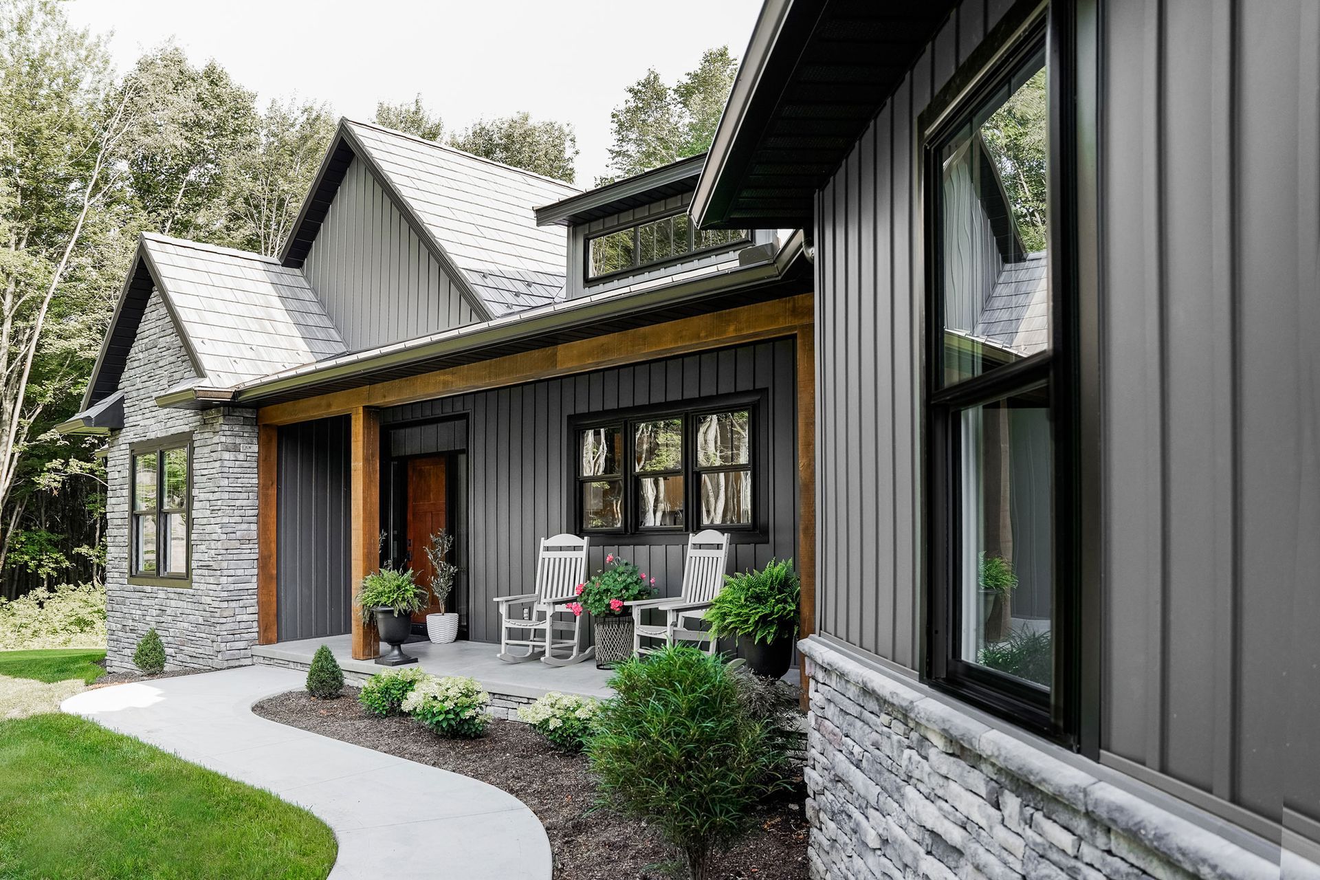 Gray modern house with stone accents, covered porch, and black window frames.