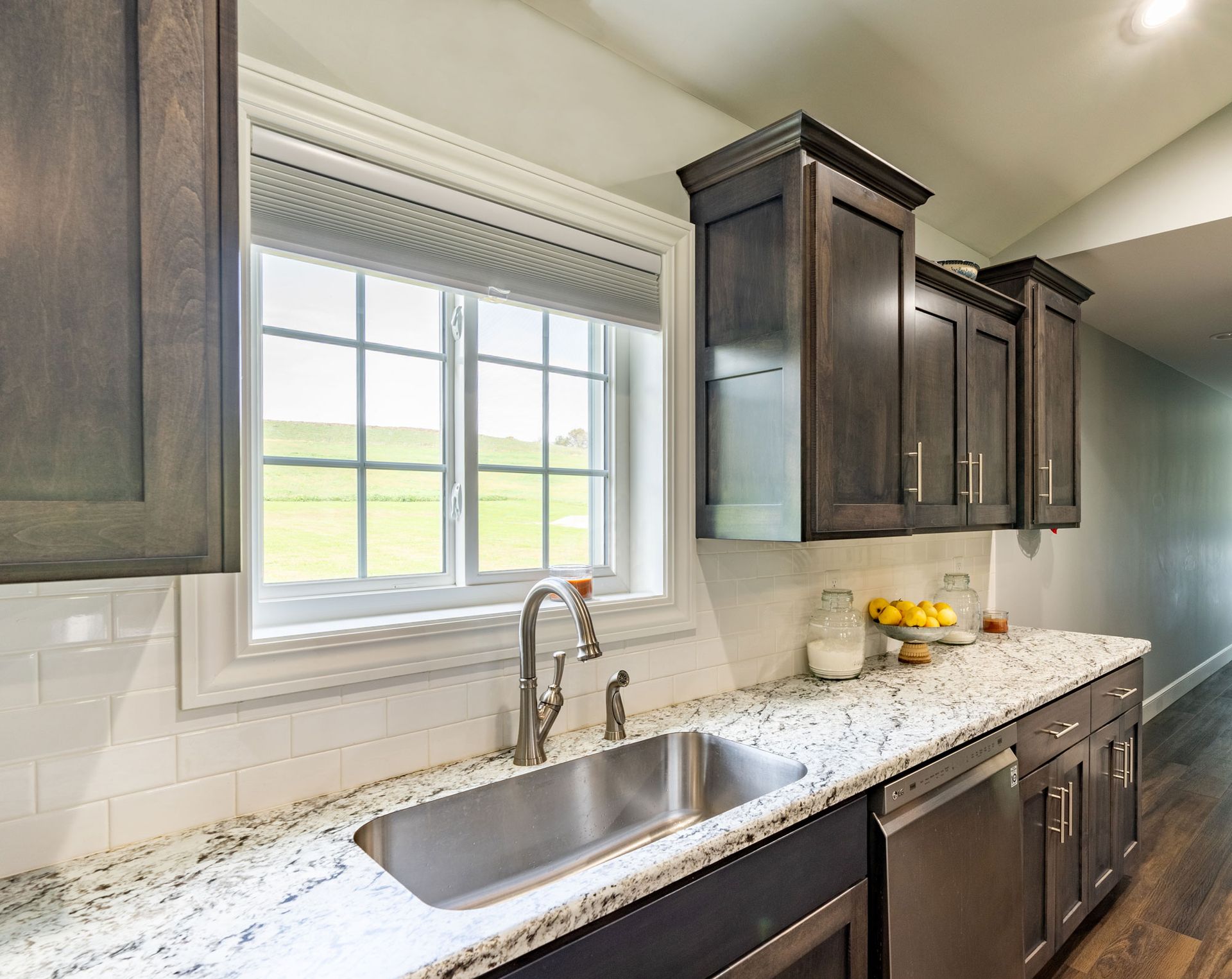 Kitchen with dark wood cabinets, granite countertops, and stainless steel sink.