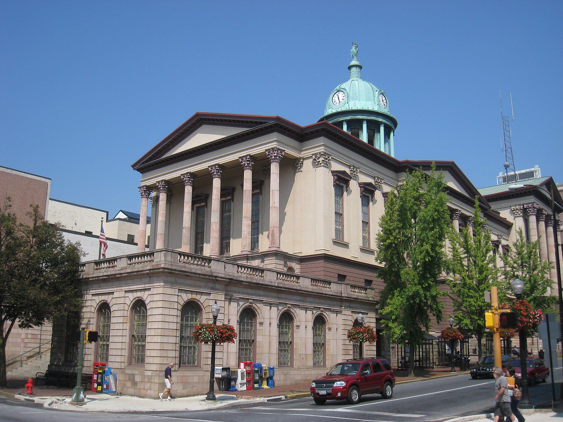 Historic building with columns and a copper dome, street corner setting.