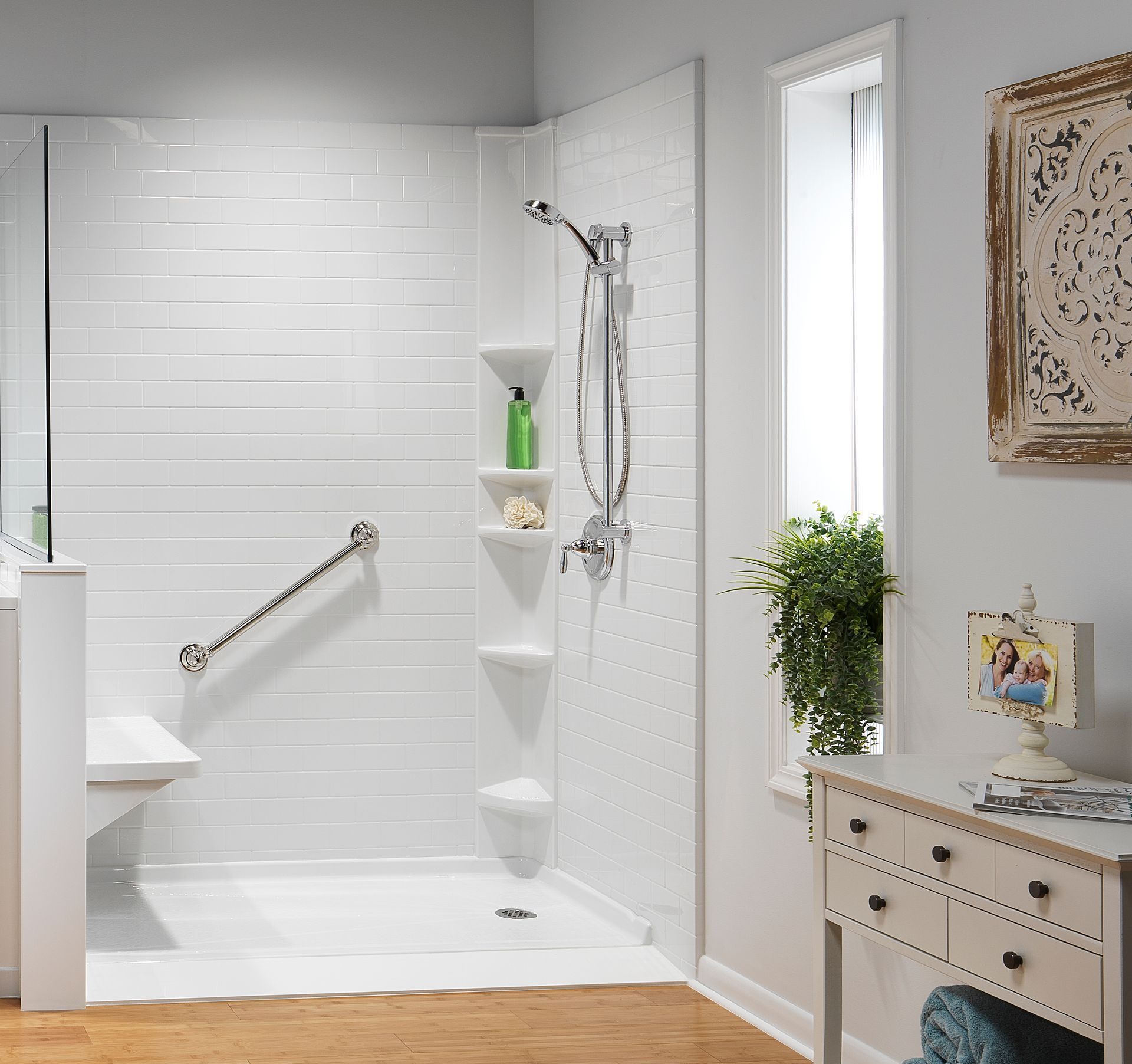 Accessible white shower with built-in seat, grab bar, and multiple shelves; bathroom interior.