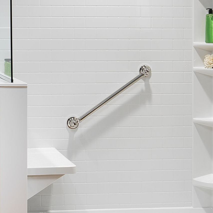 White-tiled shower wall with a silver grab bar and a built-in bench.