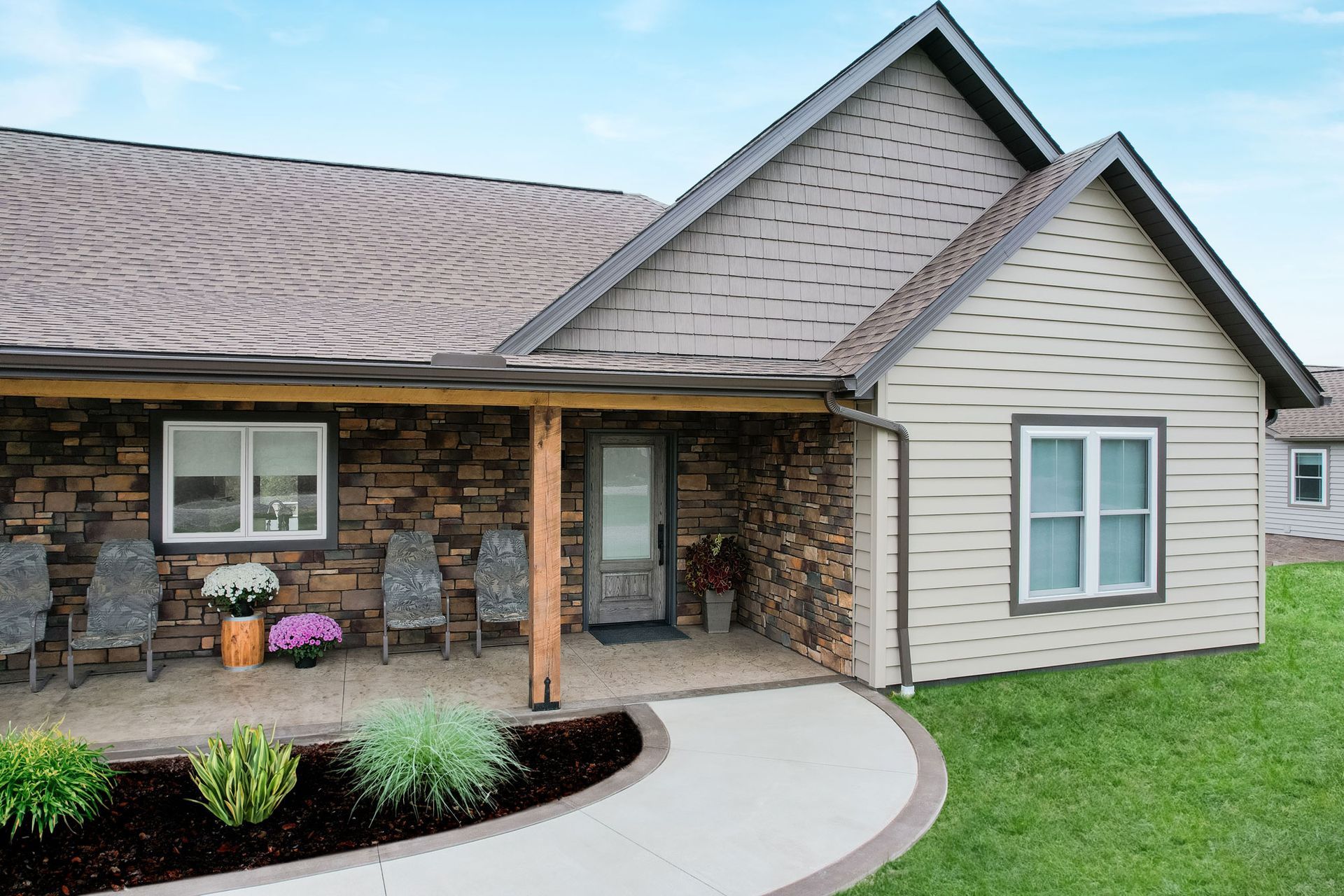 Exterior view of a ranch-style house with stone and beige siding, a covered porch, and a curving walkway.