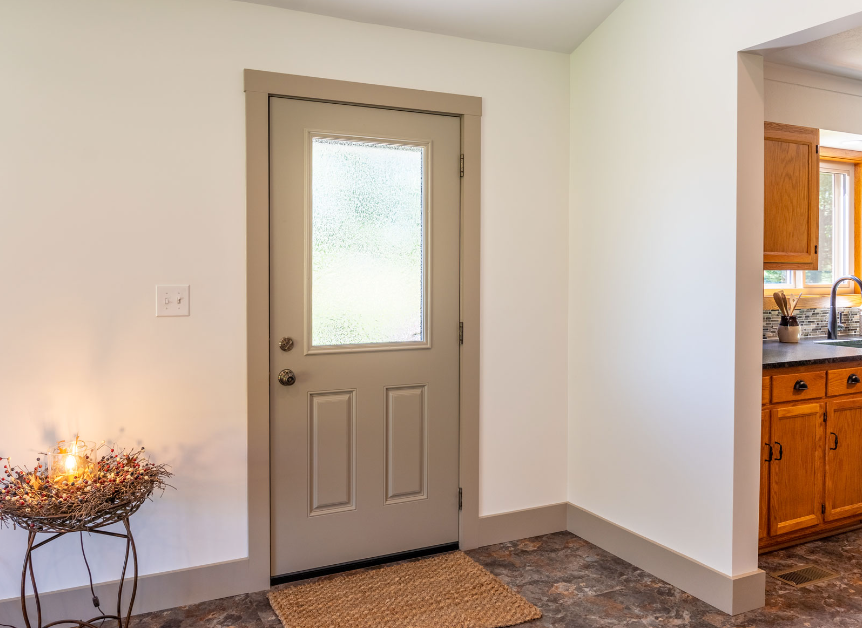 Beige door with frosted glass panel and tan trim, leading outside; interior entry with tile floor.
