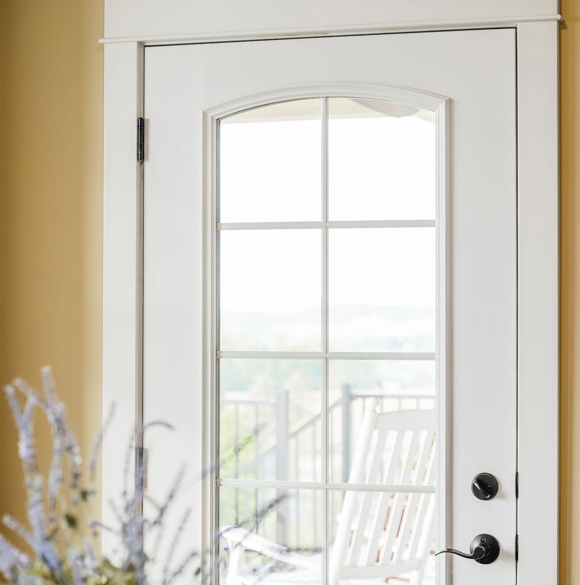 White door with glass panes, leading to a balcony with a white chair.