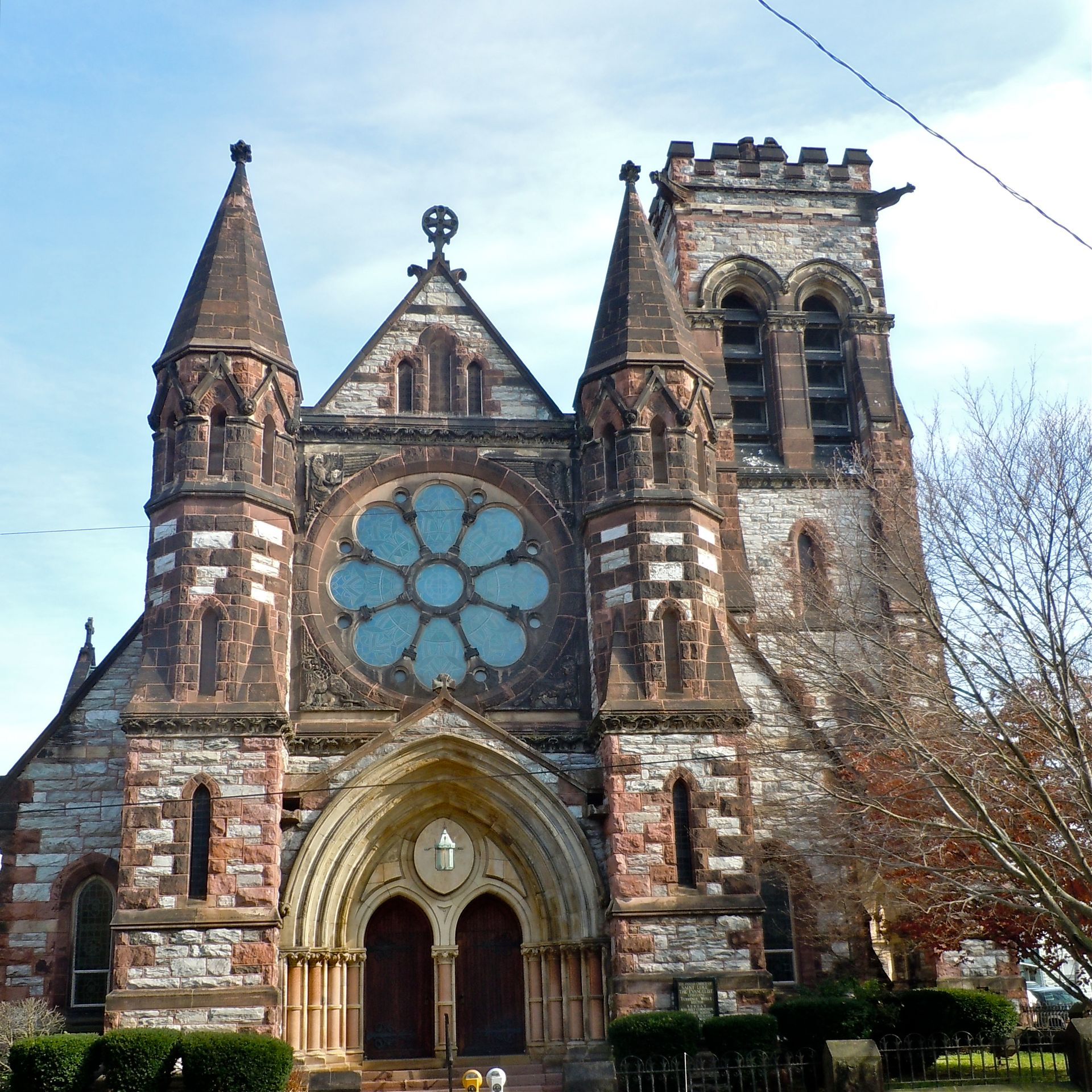Stone church with rose window and tower against a blue sky.