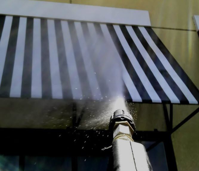 A black and white awning is being sprayed with water