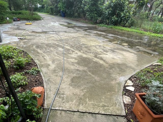 A concrete walkway is being cleaned with a pressure washer.