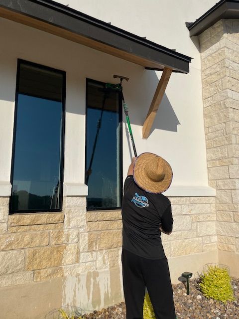 A man wearing a straw hat is cleaning a window