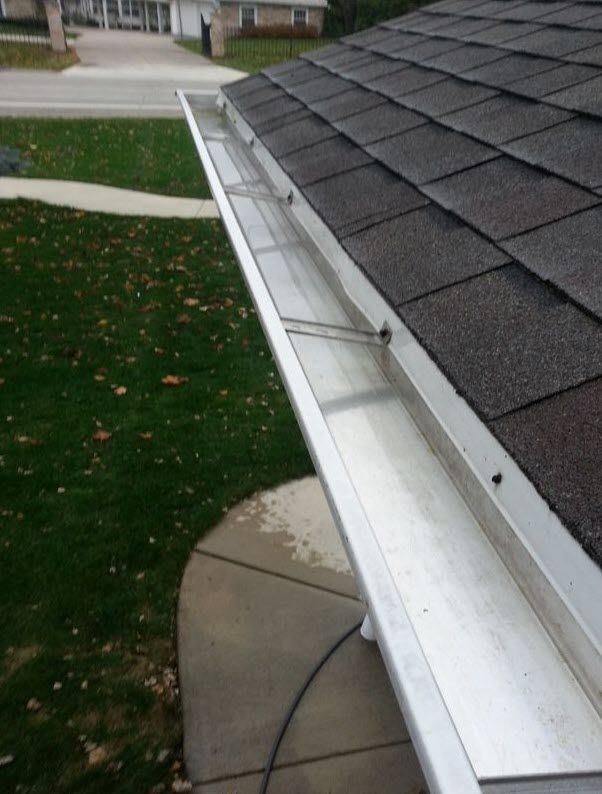 A gutter on the side of a house with shingles