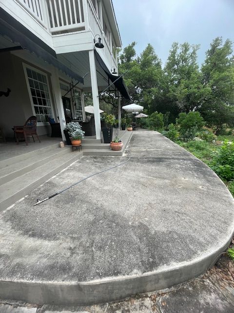 A concrete patio with a white house in the background
