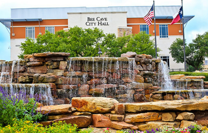 A waterfall is in front of the bee cave city hall.