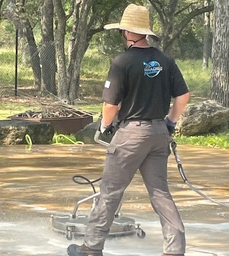 A man wearing a hat and a black shirt is standing on a concrete surface.