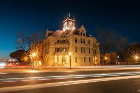 A large building with a clock tower is lit up at night.