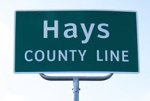 A green sign that says hays county line