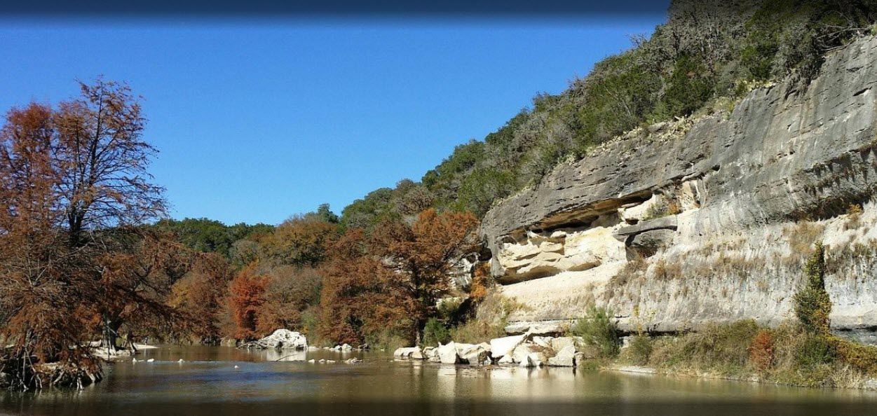 A river surrounded by trees and rocks on a sunny day