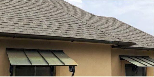A house with a roof and awnings on the windows.