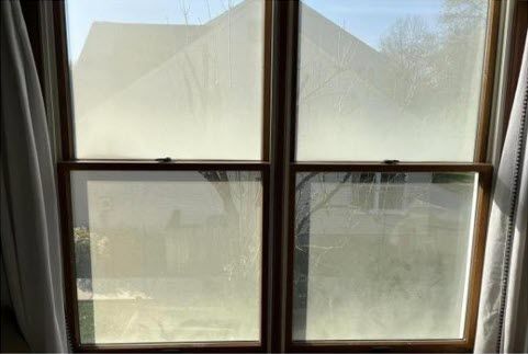 A window with frosted glass in a room with curtains.