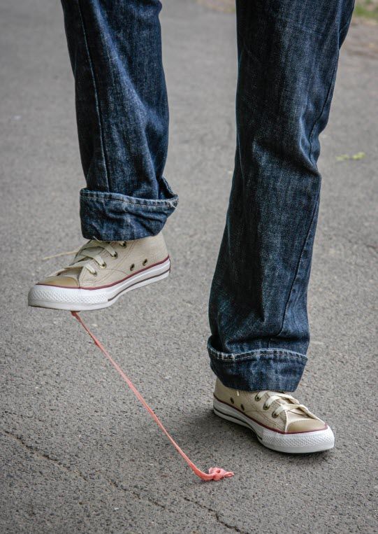 A person is chewing gum on the ground while wearing converse shoes.