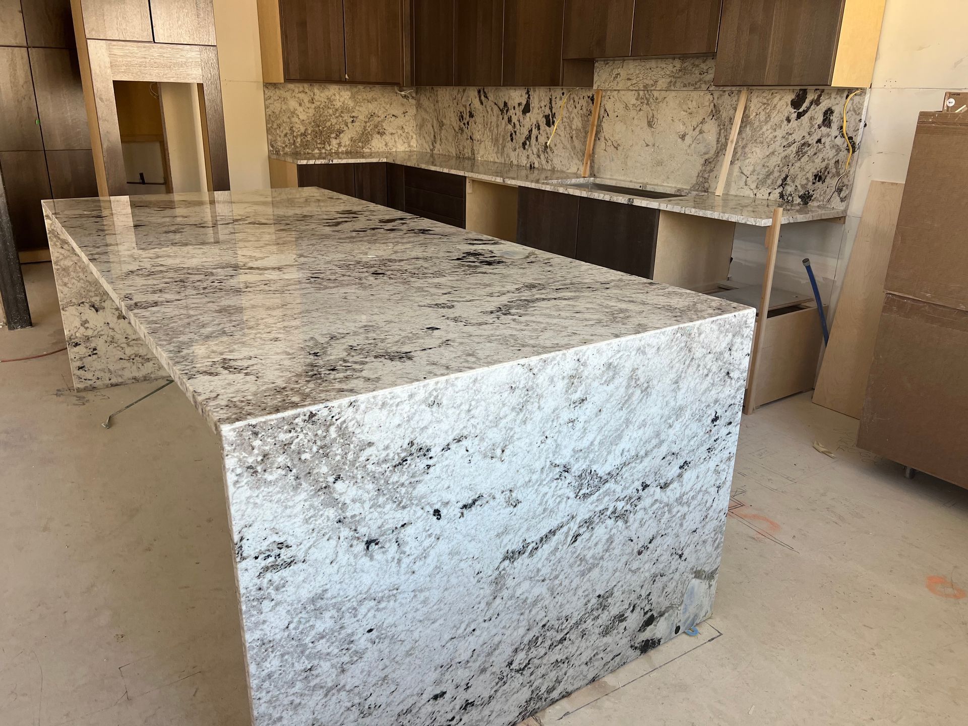 Large white-and-gray speckled granite kitchen island in an unfinished room