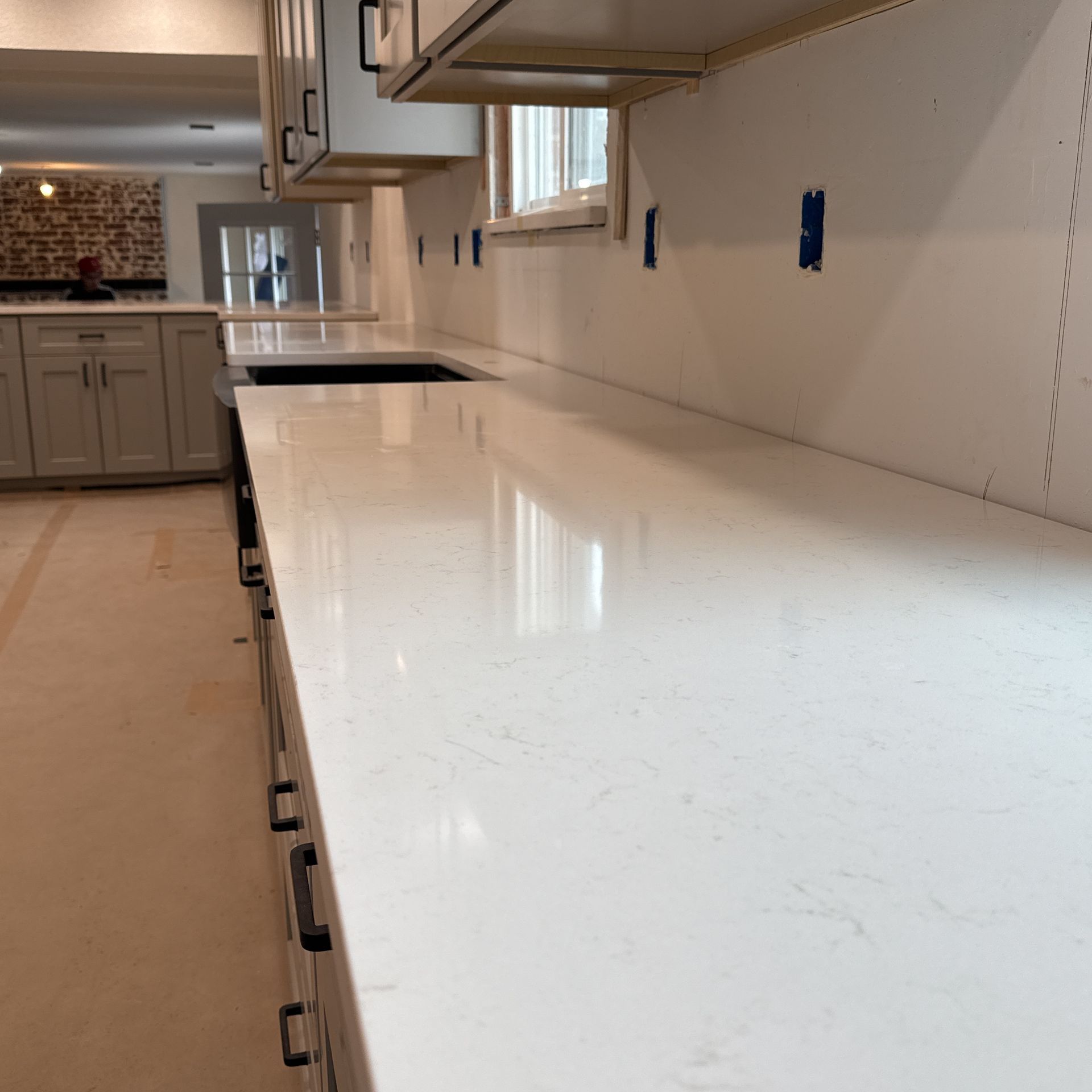 Bright white kitchen countertop with cabinets and a backsplash under construction