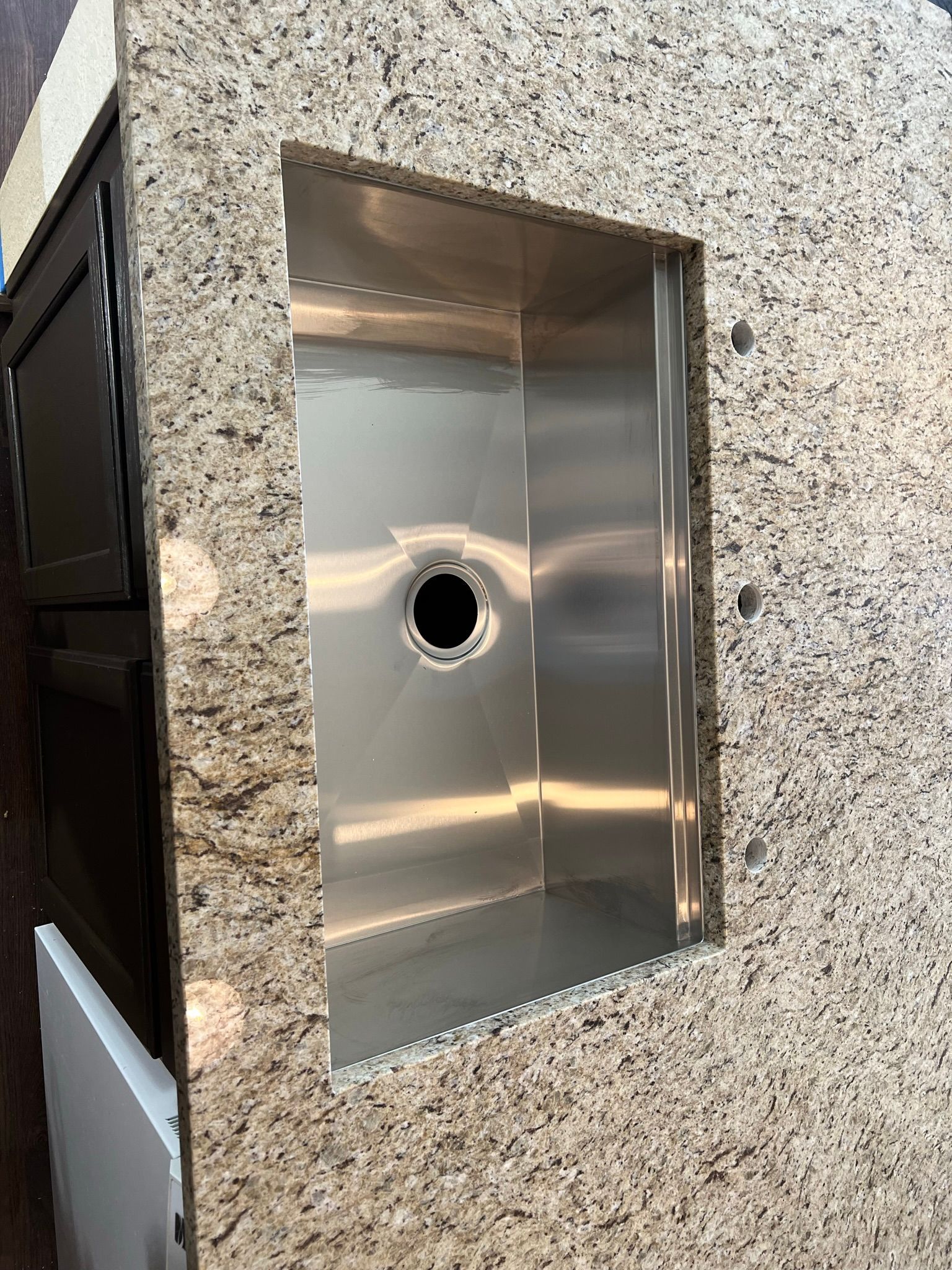 Stainless steel recessed wall panel with a circular hole, set in a speckled stone wall.