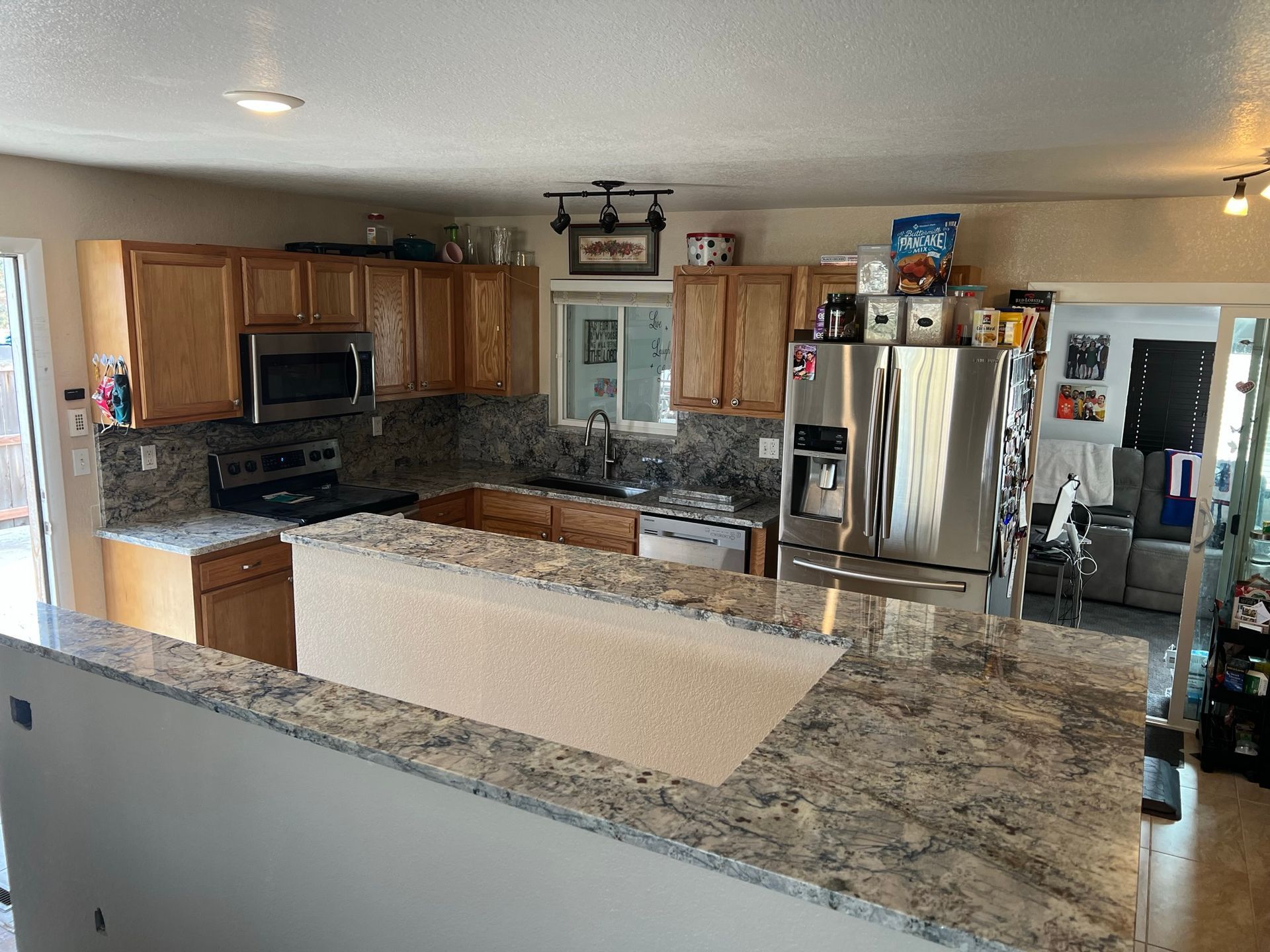Spacious kitchen with granite counters, wood cabinets, stainless fridge, and tiled floor