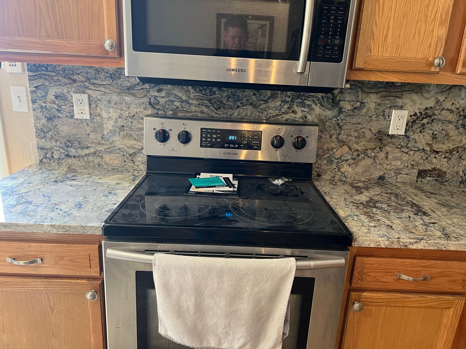 Kitchen with stainless steel oven and microwave, granite counters, and a towel hanging on the oven handle.
