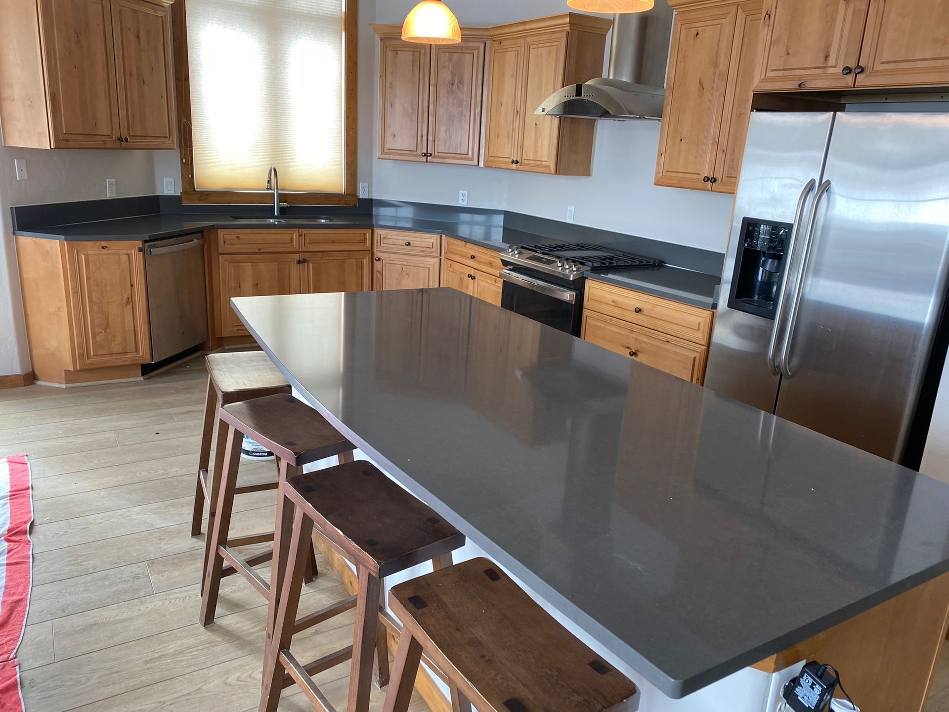 Modern kitchen with wood cabinets, stainless appliances, and a large gray island with stools