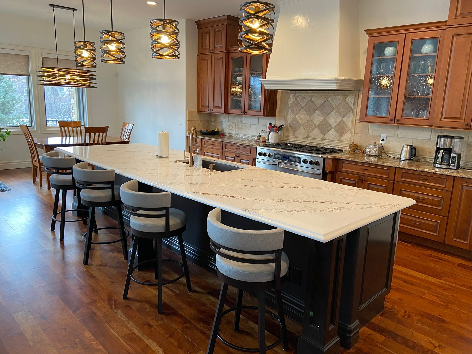 Spacious modern kitchen with a long island, pendant lights, wood cabinets, and barstools