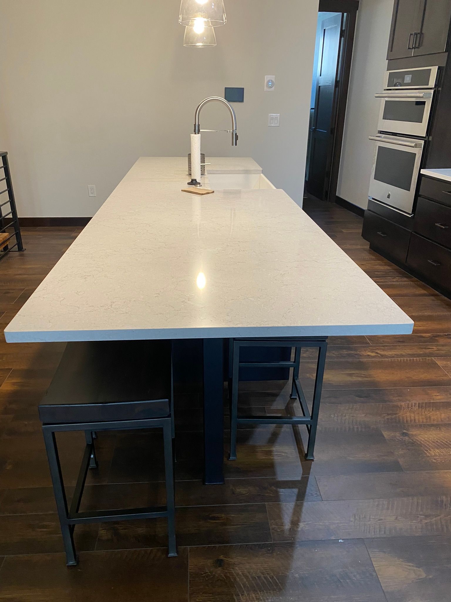 Kitchen island with white countertop, chrome faucet, and two black stools in a modern kitchen