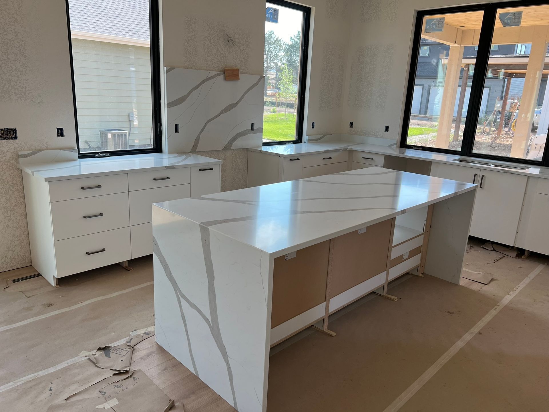 Modern kitchen with white cabinets and a large island in an unfinished room