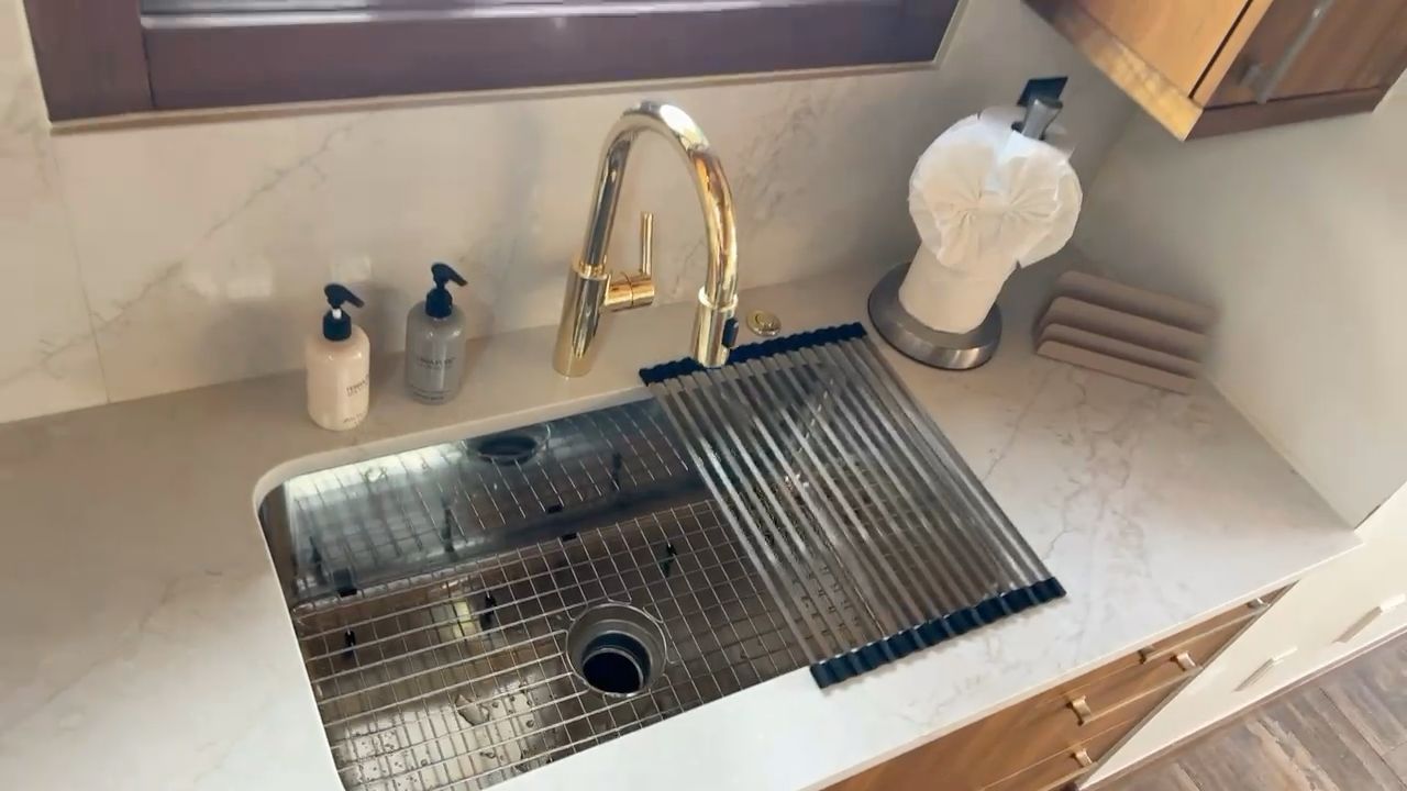Kitchen sink with a ribbed drying rack, faucet, soap dispensers, and a water filter on the counter