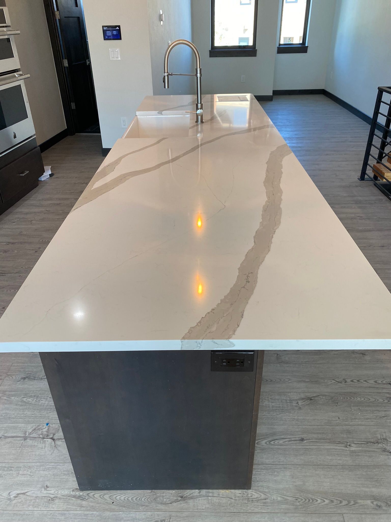 Kitchen island with white countertop and stainless sink in a modern interior