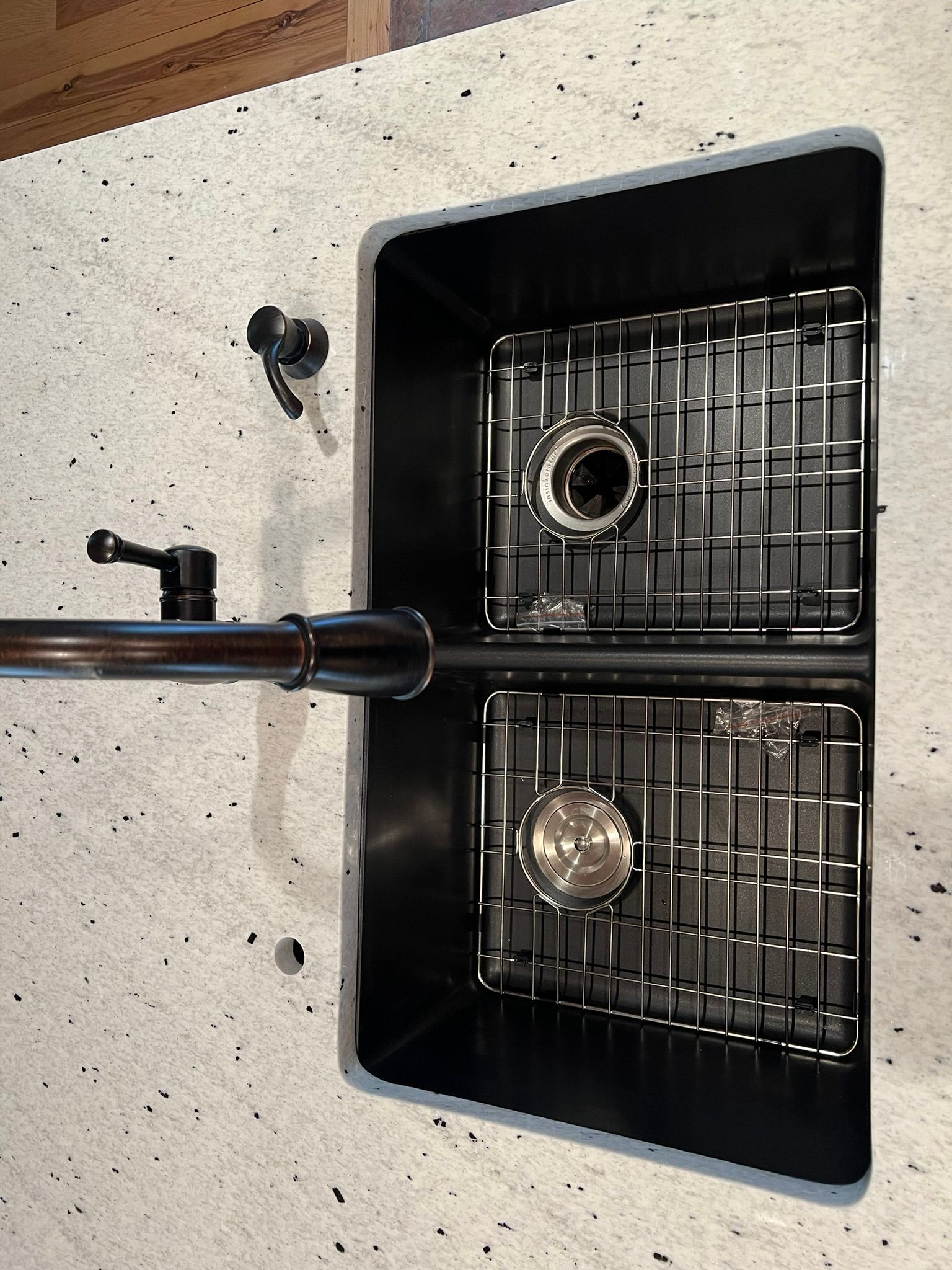 Black double kitchen sink with a faucet and drain strainers, viewed from above.