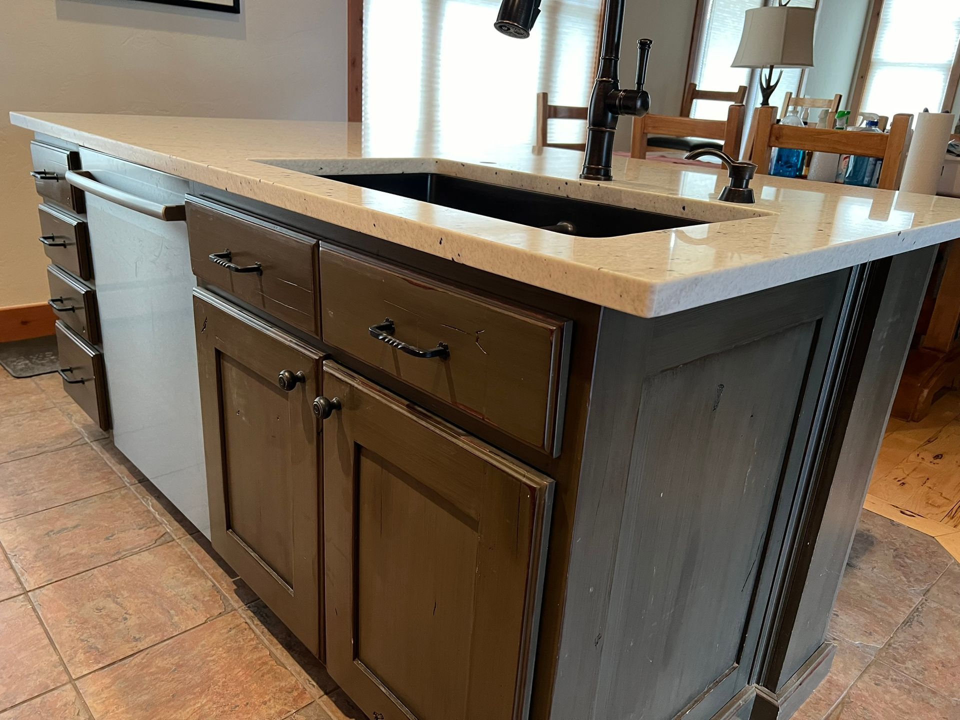 Kitchen island with dark wood cabinets and a light stone countertop in a tiled room