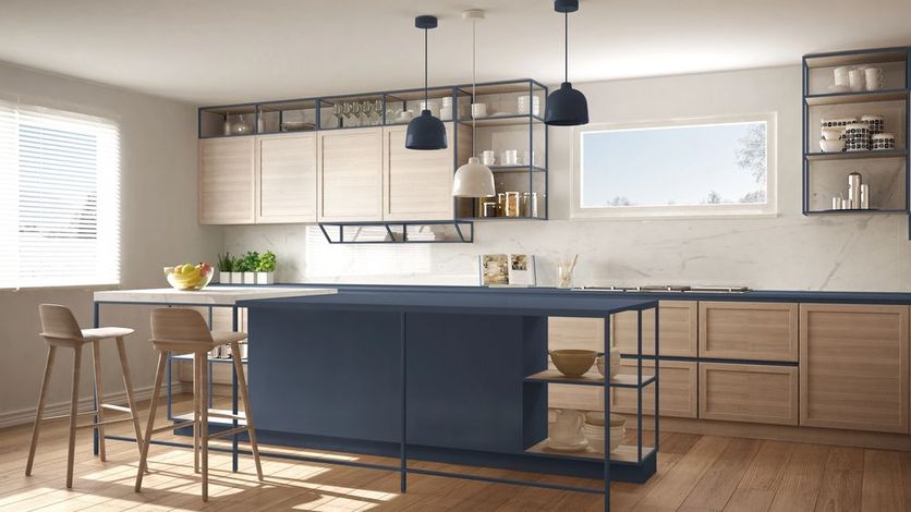 Cucina moderna con isola blu navy, mobili in legno chiaro, sgabelli e finestre luminose.