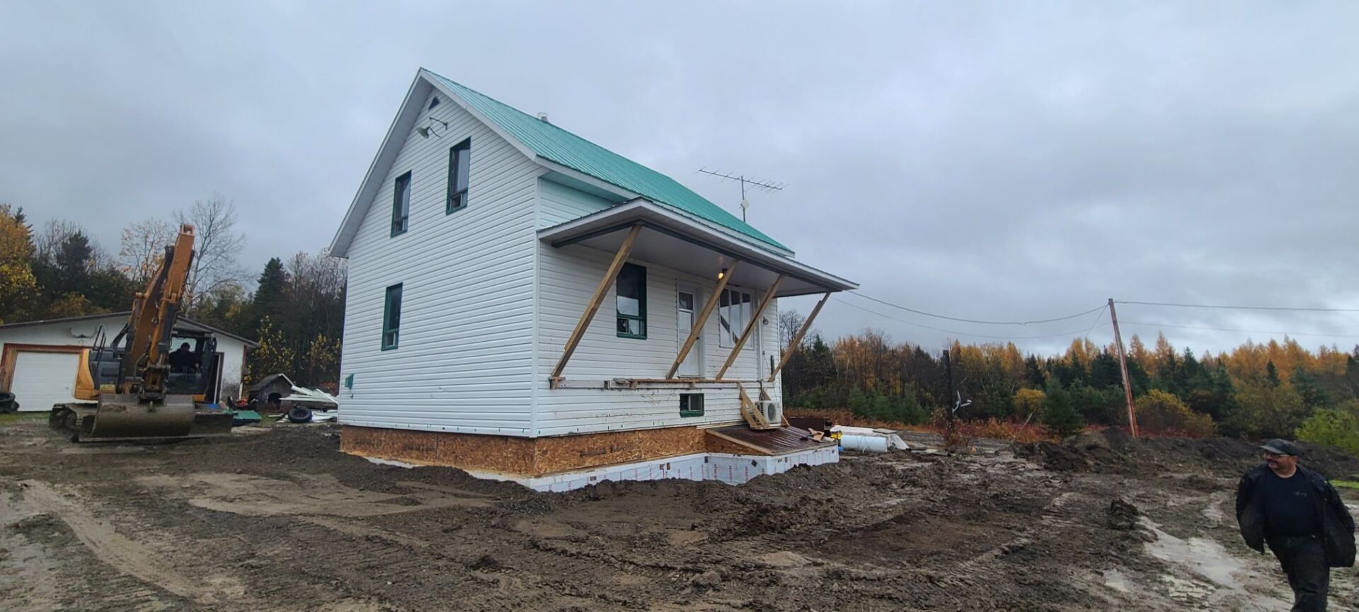 Une maison blanche est en construction au milieu d'un champ de terre.