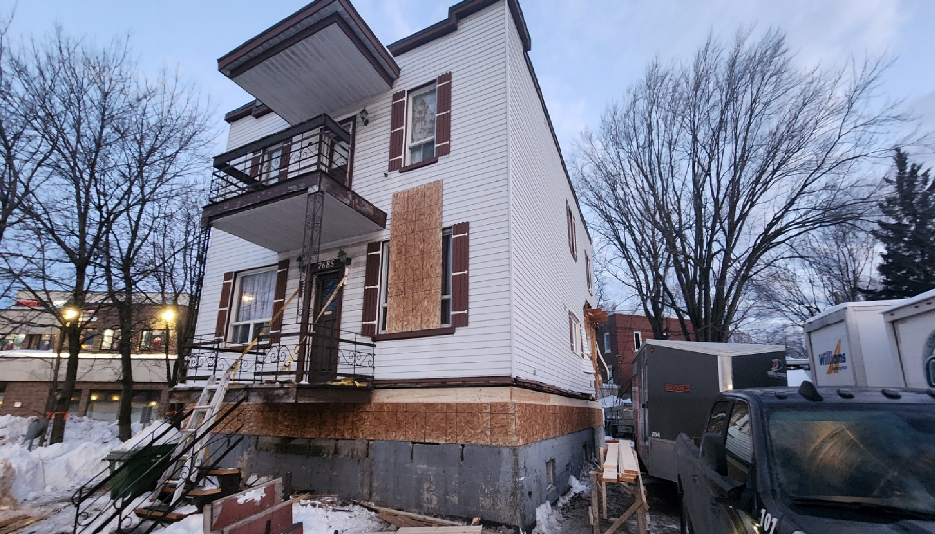 Une grande maison blanche est en cours de rénovation sous la neige.