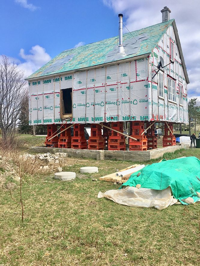Une maison est en train d'être construite sur pilotis dans un champ herbeux.