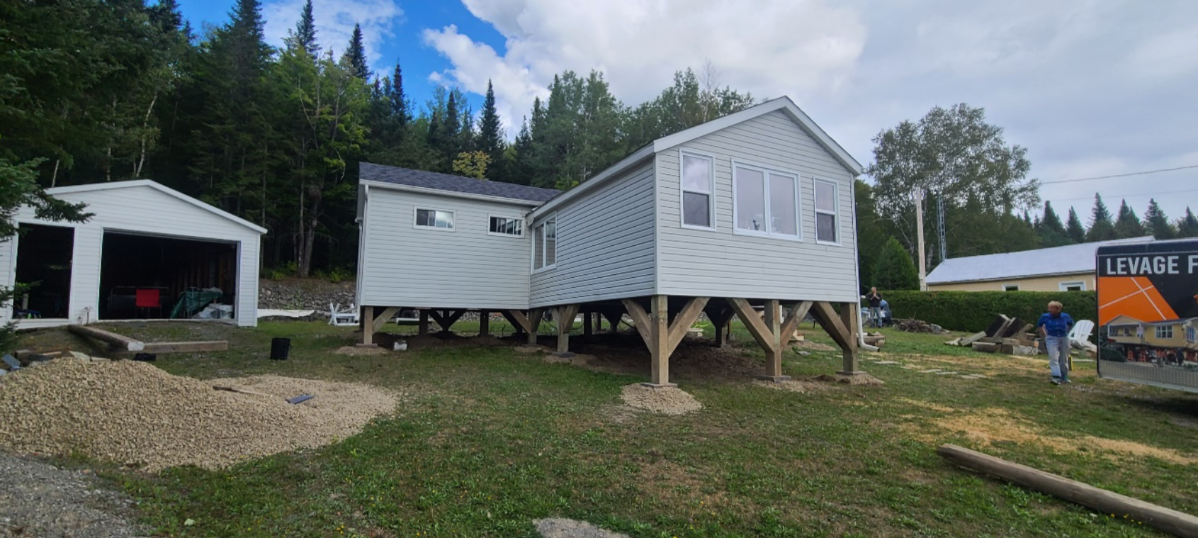 Une maison mobile est en cours de construction sur pilotis dans une cour.