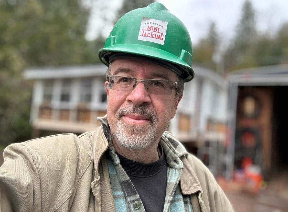 Un homme portant un casque vert et des lunettes prend un selfie.
