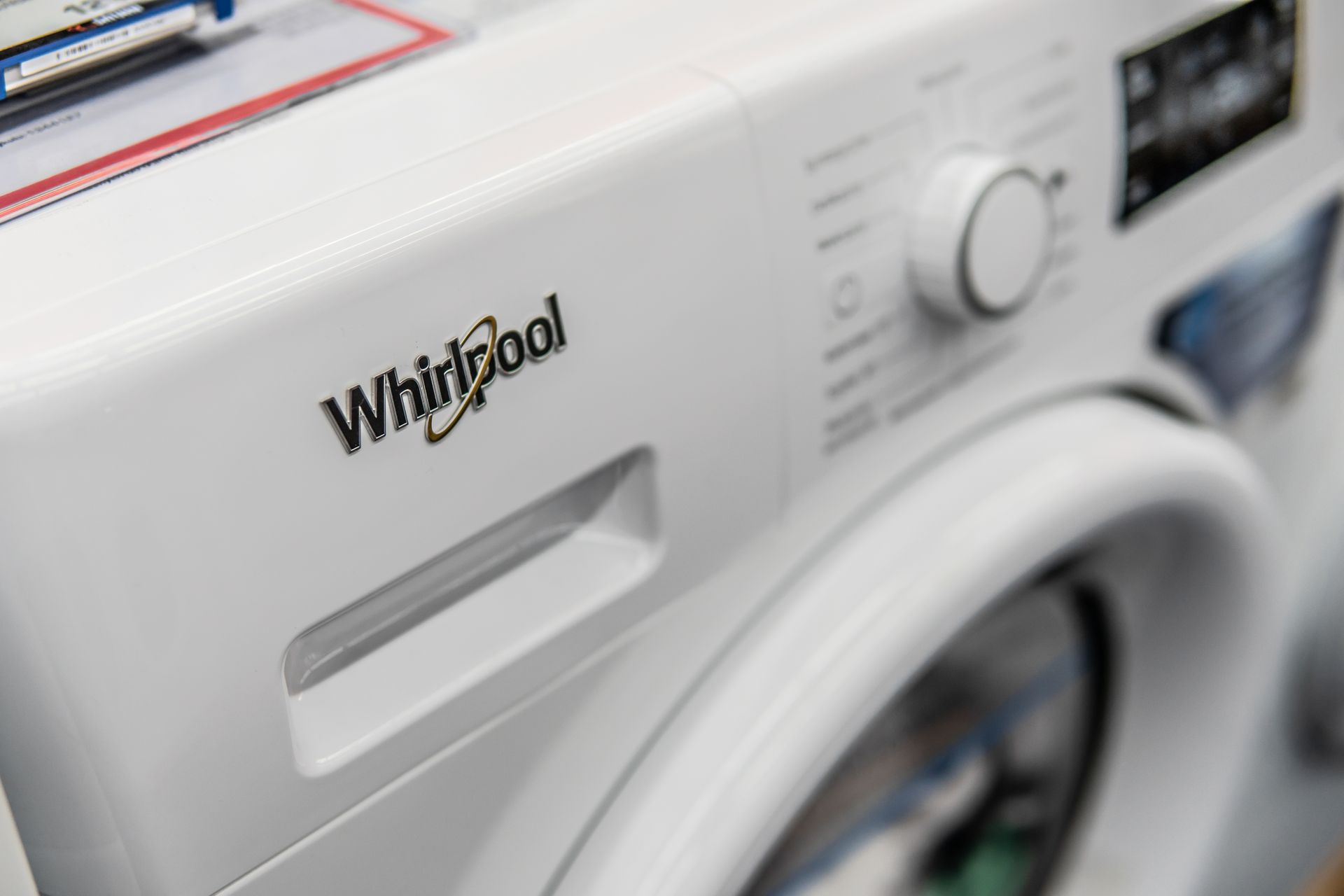White Whirlpool washing machine control panel and door in a laundry room close-up