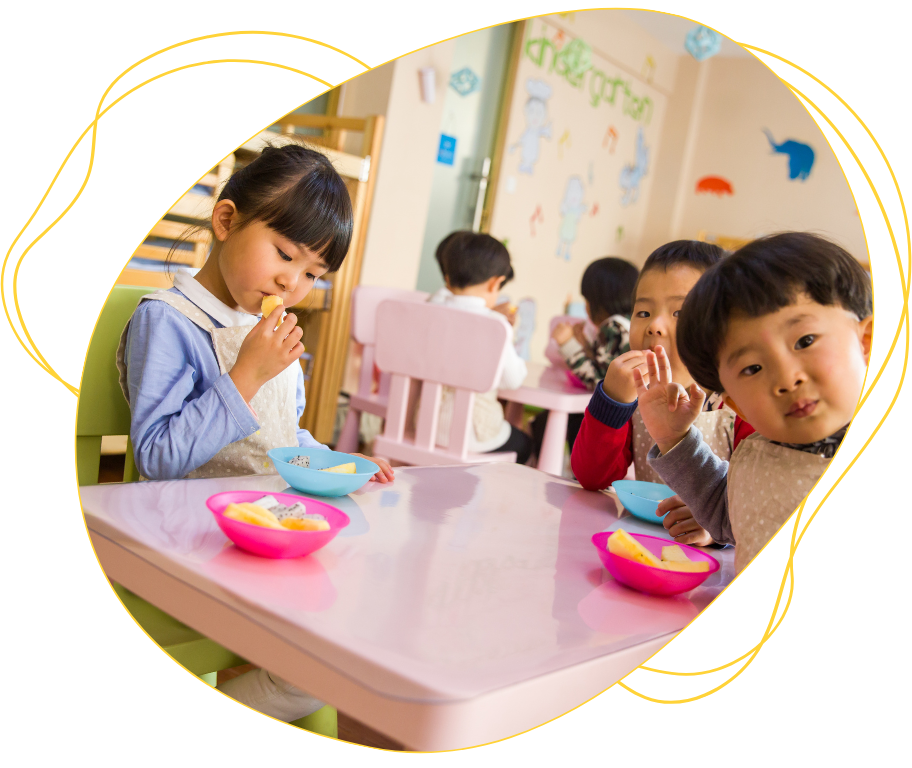A group of children are sitting at a table eating food.